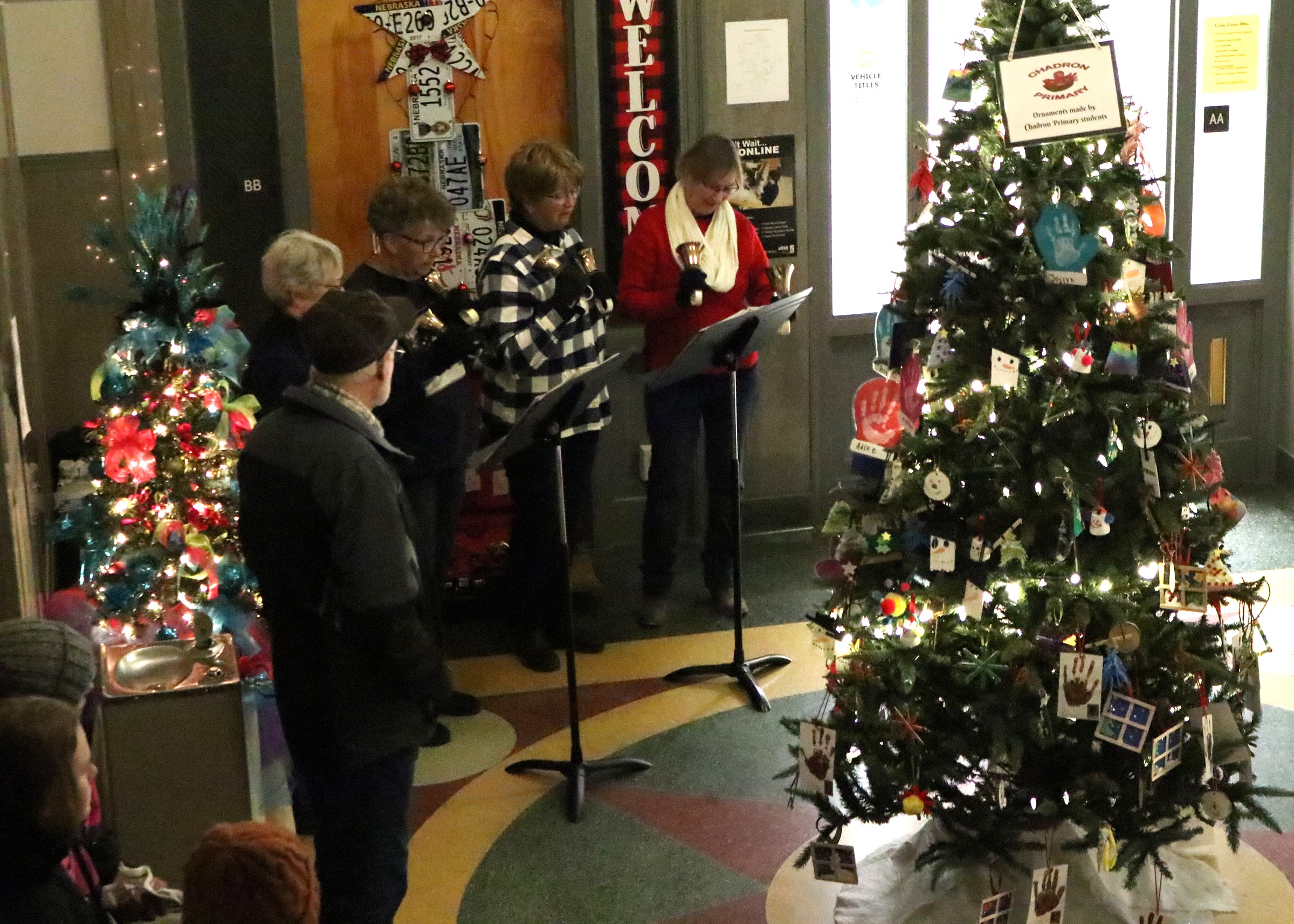 A group of women sing Christmas carols surrounding a Christmas tree.