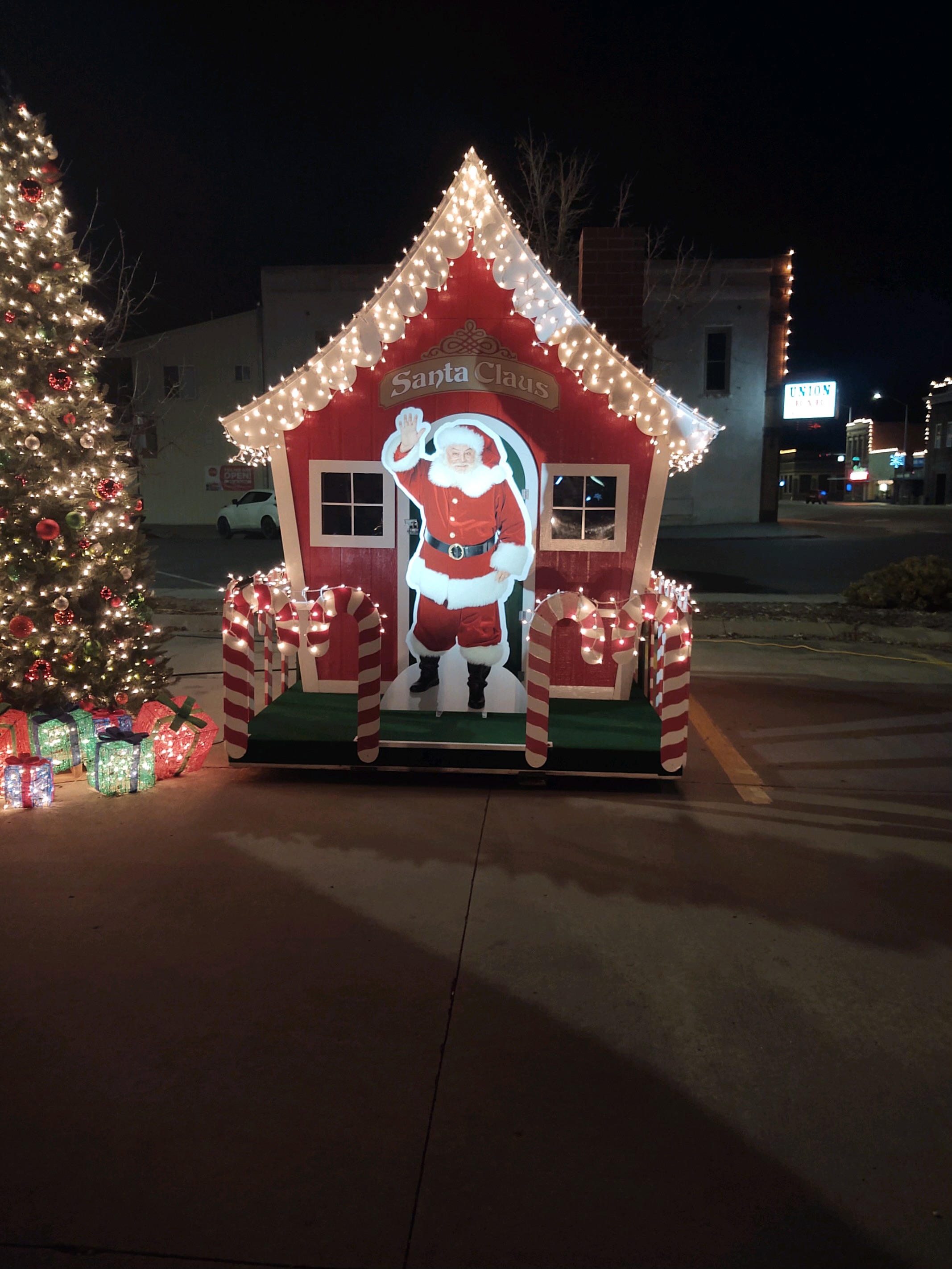 Outside view of Santa Clauses Village with Christmas lights and a Christmas tree surrounding.