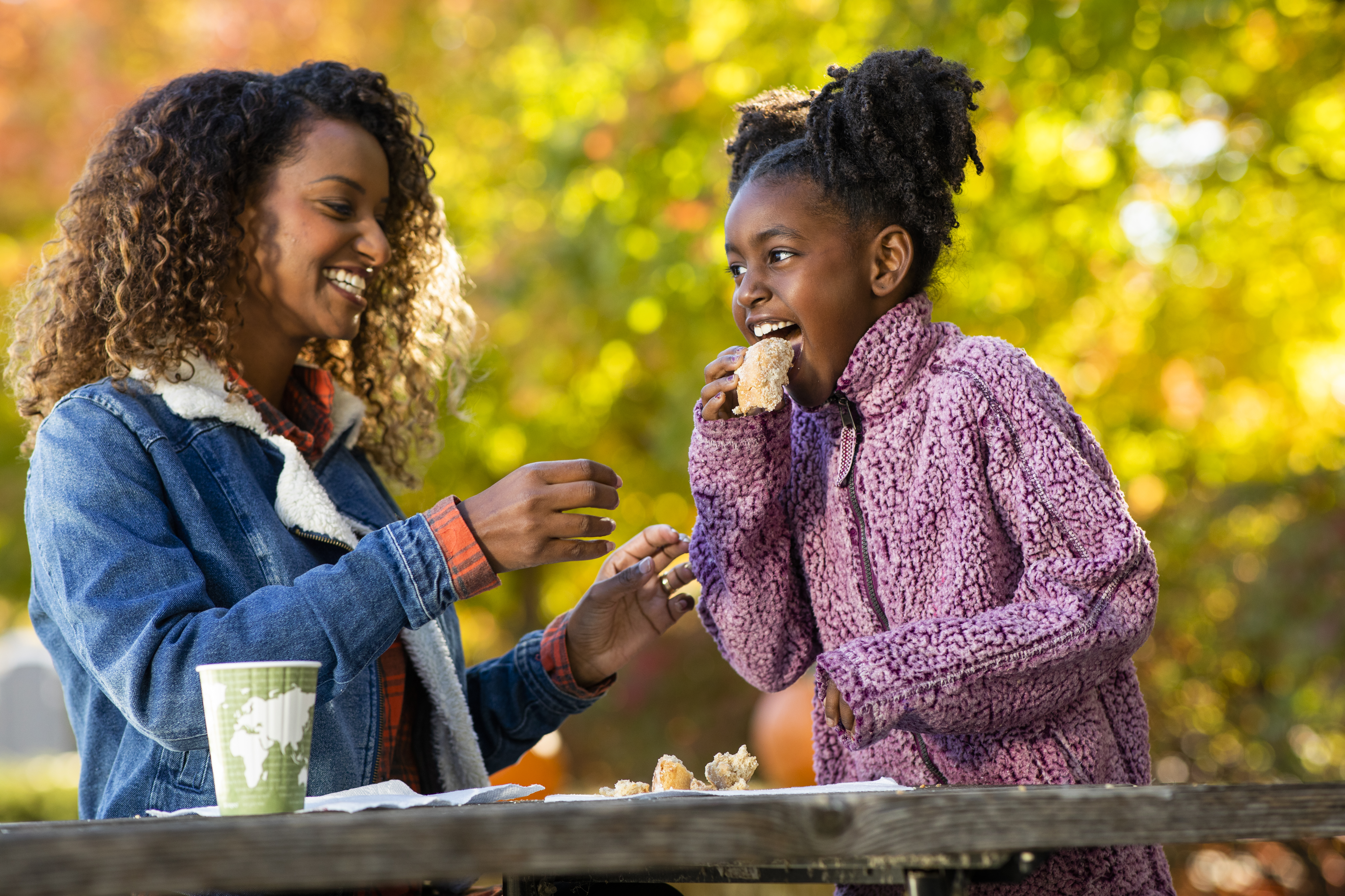 A mother and daughter sharing a treat on a picnic.