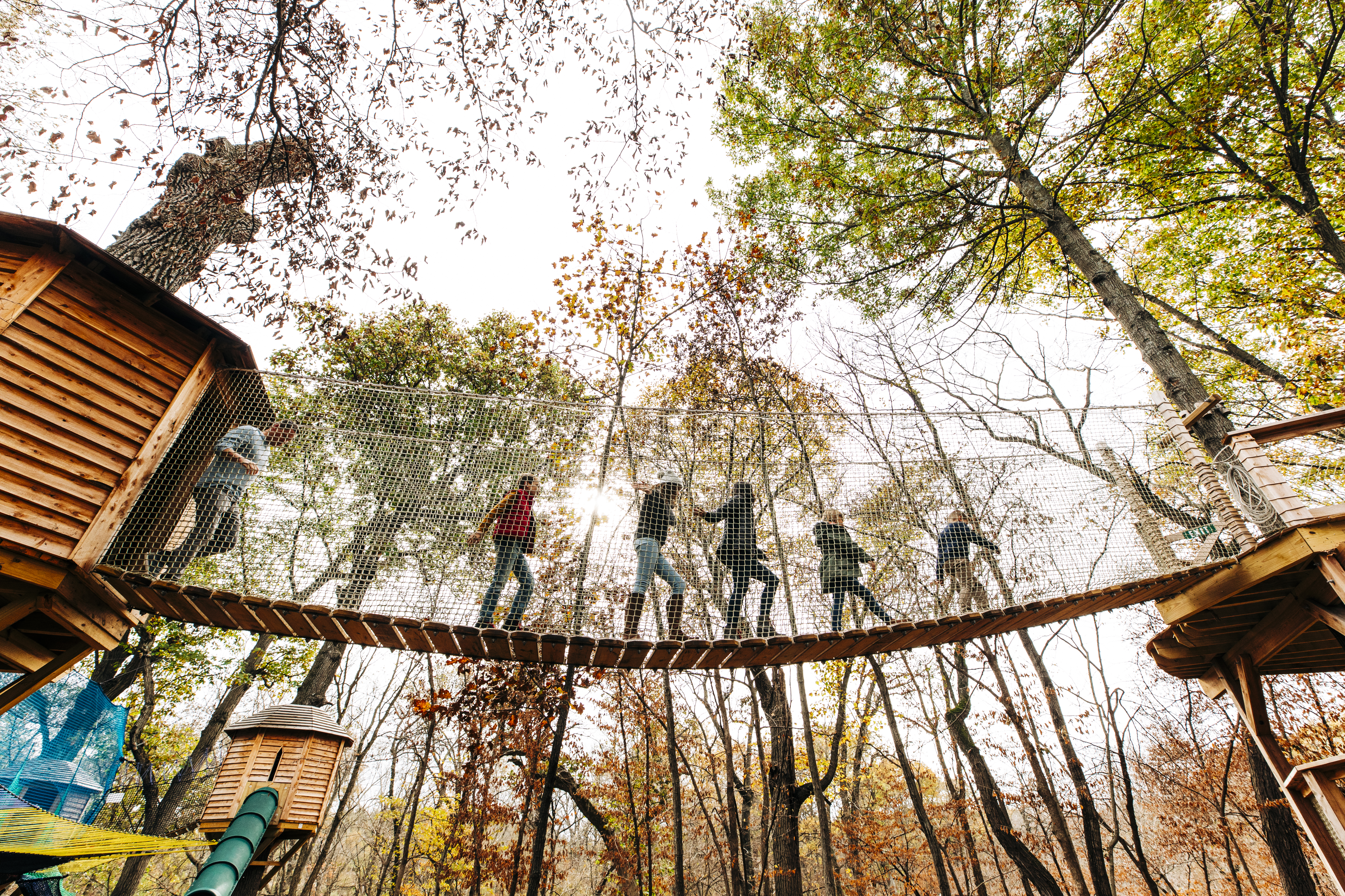 A family crossing a bridge on Tree Adventure at Arbor Day Farm.