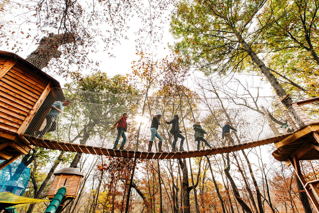 A family of six crossing a bridge on Arbor Day Farm's Tree House Trail. | Geoff Johnson