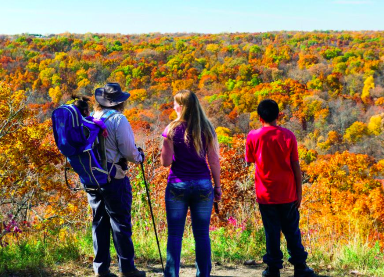 Three hikers, one carrying a toddler on his back, take in Nebraska's fall colors.