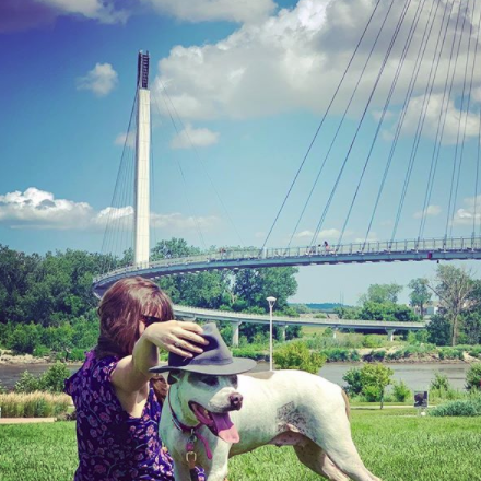 woman and dog in park by pedestrian bridge