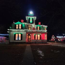 Outside of a historical house with Christmas lights decorating it.