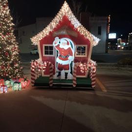 Outside view of Santa Clauses Village with Christmas lights and a Christmas tree surrounding.