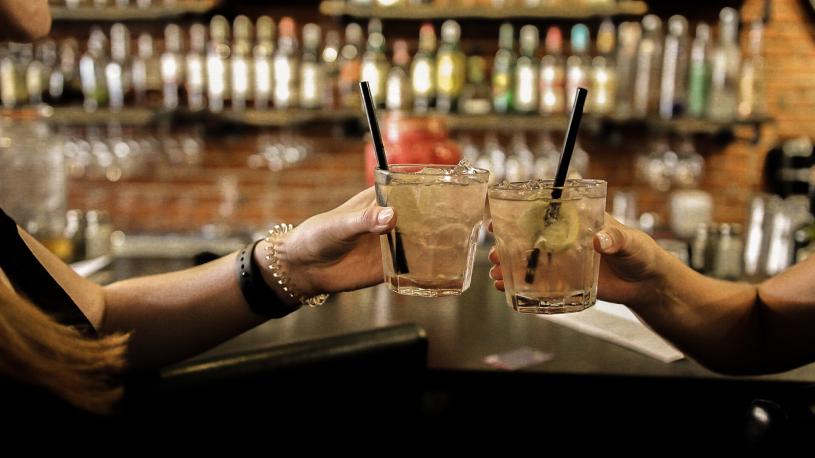 Guests tapping cocktail glasses at the bar at Odyssey.