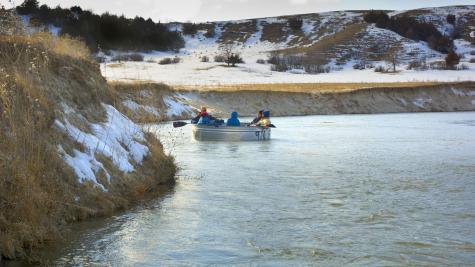 Group floating down the river in a stock tank surrounded by a snowy landscape. 